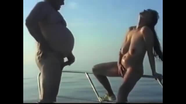 Nude mature German amateur woman with saggy tits masturbates on boat railing beside fat man