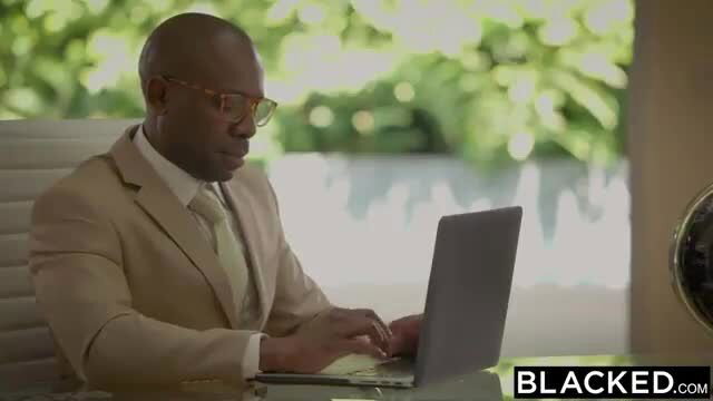 Black suited man works on laptop in office, Lily Rader Blacked scene