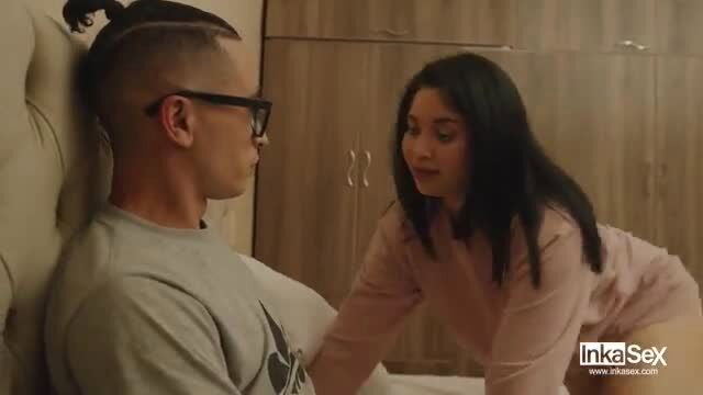 Asian woman in pink top leans over man on bed in intimate scene