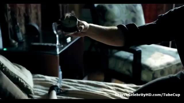 Man in suit holding syringe over nude woman on bed in dark bedroom