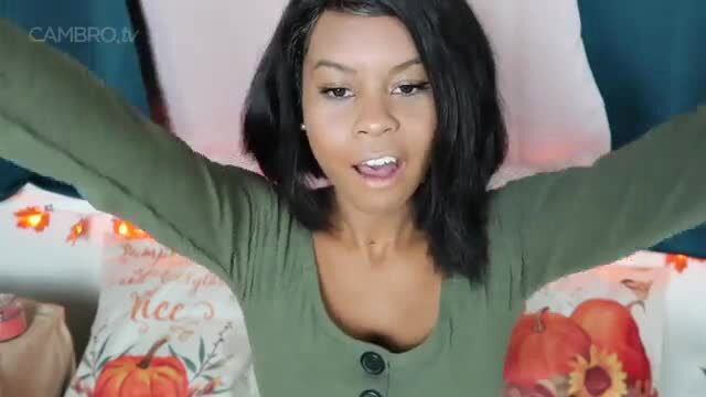 Vixxi in a green top, smiling with arms raised