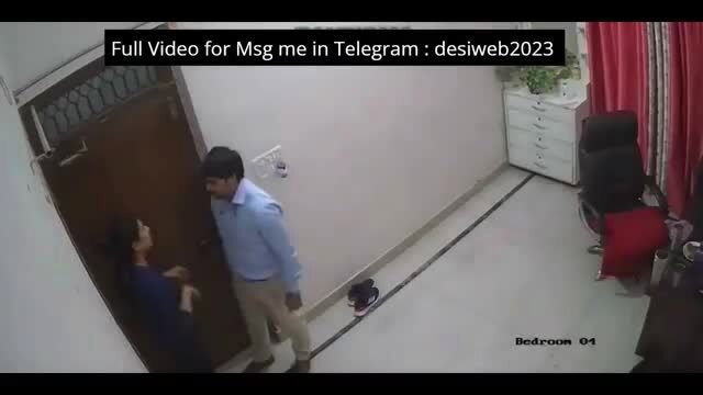 Indian man in shirt presses against woman in blue dress by door