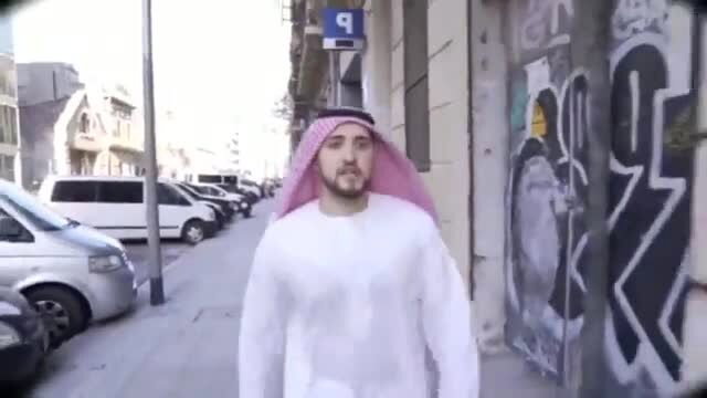 Arab Muslim man in white thobe and pink headscarf walking on urban street