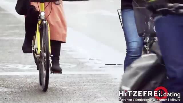 Two women in skirts and jeans by yellow bike on street, outdoor tease