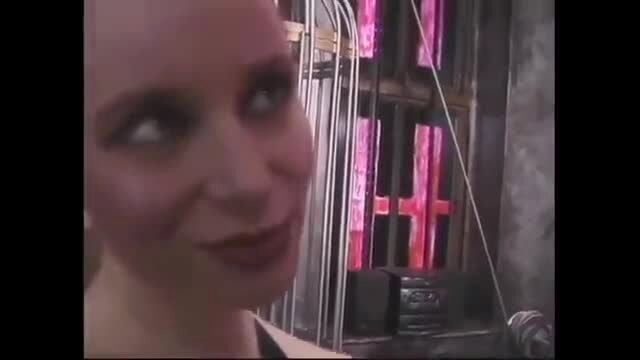 Bald mature lesbian smiling in BDSM dungeon