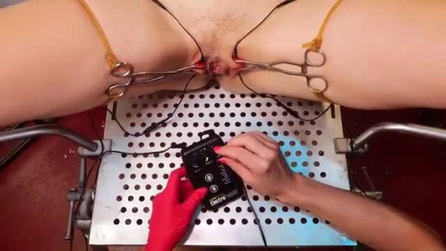 Woman in bondage chair with labia clamps and electro stim device ready for sounding