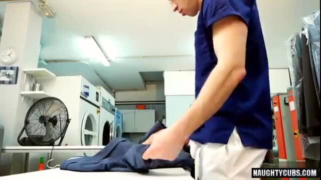 Hot Asian guy in scrubs folding laundry at laundromat