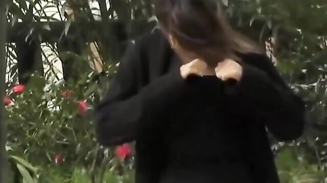 Nerdy brunette tricked in park, hands pulling black sweater open outdoors