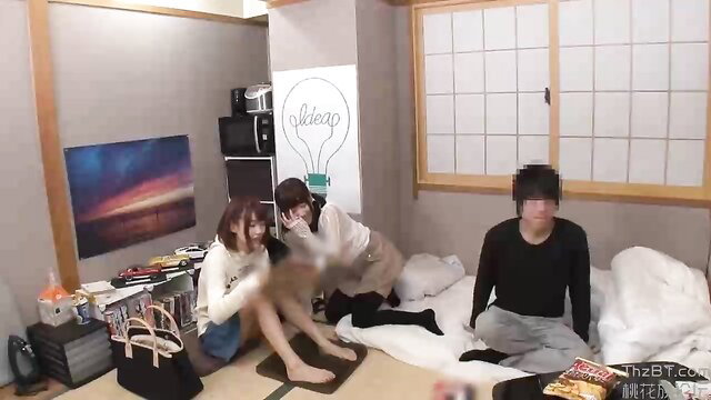 Japanese girls wrestling playfully with guy on futon in JAV sleepover scene