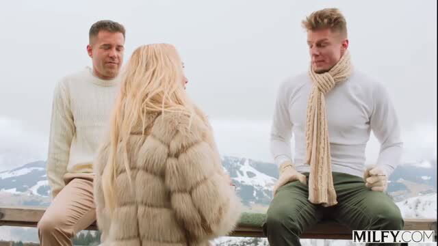 Brandi Love in fur coat with two men on snowy mountain overlook