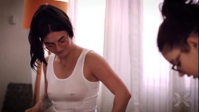 Two busty brunette Latina women in sheer white tank tops, nipples visible