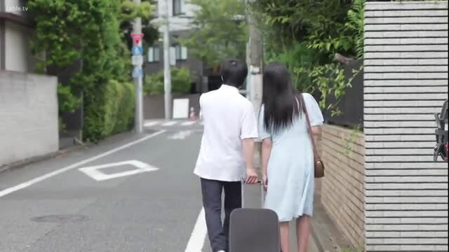 Asian couple walks hand-in-hand with suitcase on Tokyo street