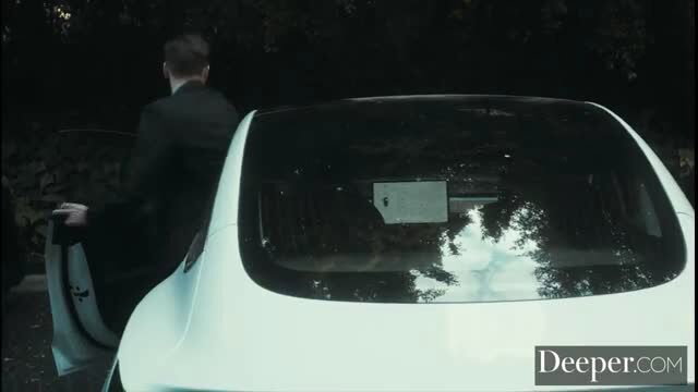 Man in suit opening white Tesla door in dark outdoor scene with Evelin Stone