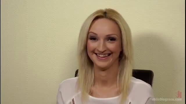 Blonde Melanie smiling in white top, Public Disgrace preview