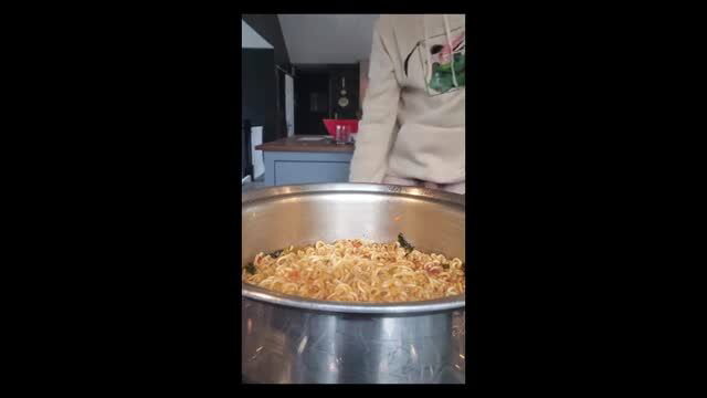 Hawt amateur chef in hoodie stirs ramen, tip kisses hot pan closeup