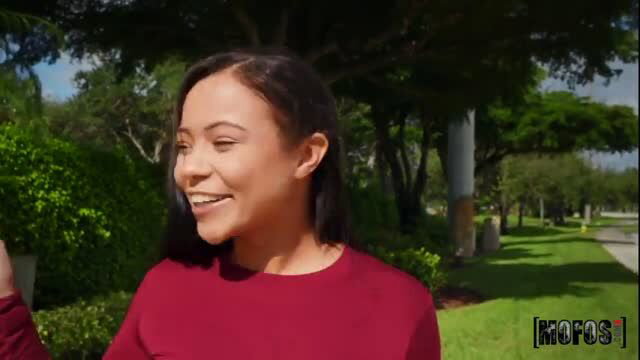 Adriana Maya smiling in red top outdoors, thick Latina stunner