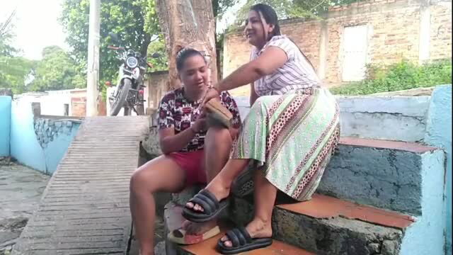 Two busty Latin women in skirts and flip flops on outdoor steps