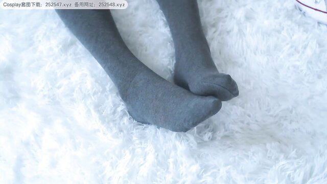 Asian girl gray stockings feet closeup on white fur bed