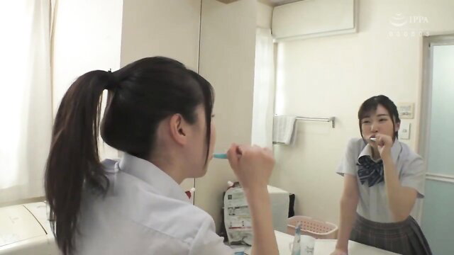 Japanese schoolgirl with ponytail brushing teeth in mirror, uniform skirt