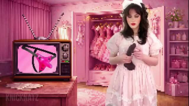 Goth girl in pink lolita dress holds dildo, watches pink thong on TV in sissy scene