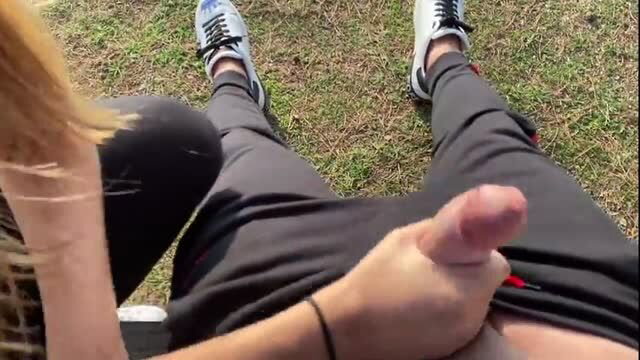 Blonde girl stroking cock POV in public park grass