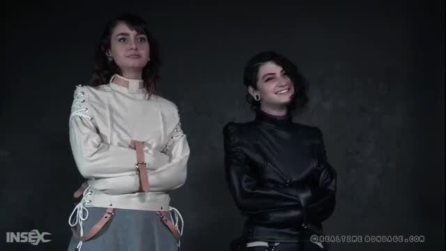 Lydia Black in white straitjacket, Ava D'Amore in leather beside her