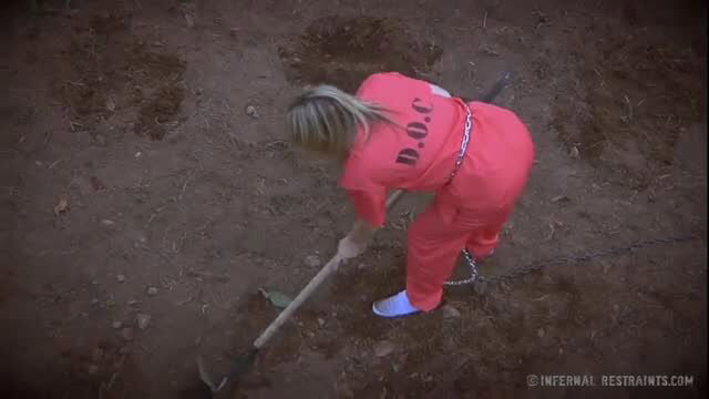 Blonde prisoner in orange jumpsuit digs chained in Infernal Restraints BDSM