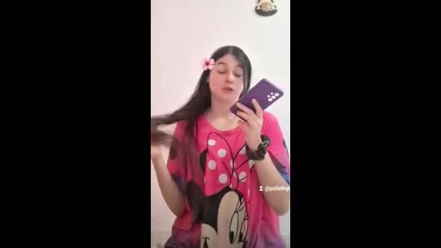 Cute teen in Minnie Mouse shirt holds phone, flirty smile