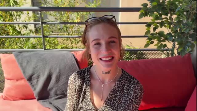 Alma smiling on balcony in leopard top, necklace, sunglasses