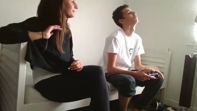 Amateur teen couple chilling on bed, girl in leggings smiles at boy gaming