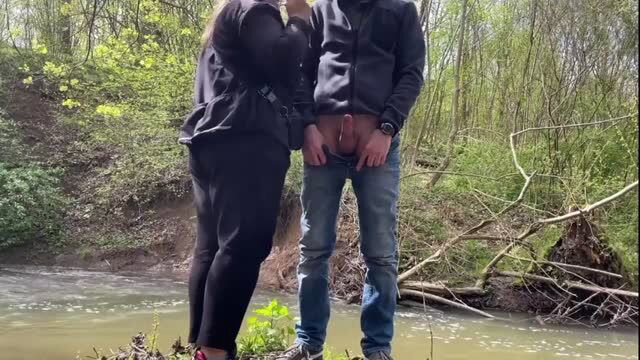 Amateur couple outdoors: woman touches man's exposed cock by river
