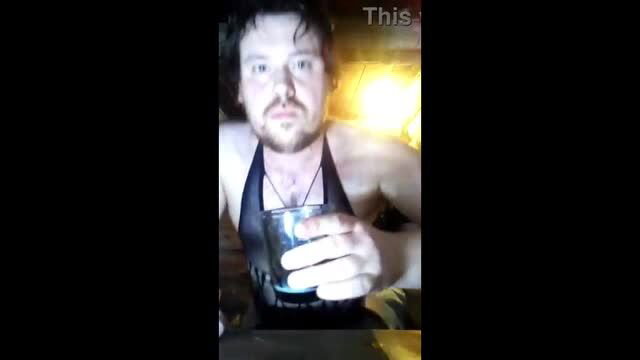 Shirtless Russian man holds drink in low-light amateur selfie