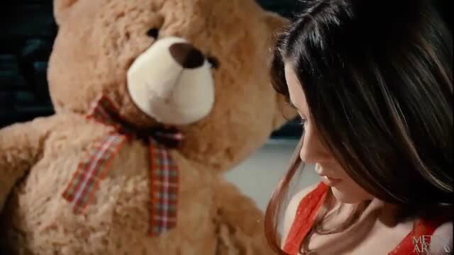 Beautiful Brunette cuddles giant teddy bear in red dress closeup