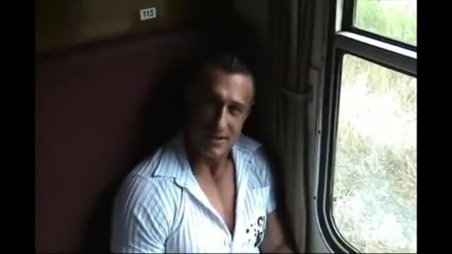 Muscular man in open shirt on train seat, intense gaze