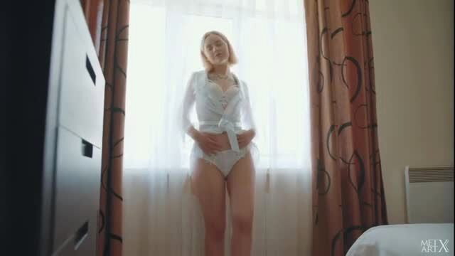Blonde babe in sheer white lingerie by window, trying on sexy gift