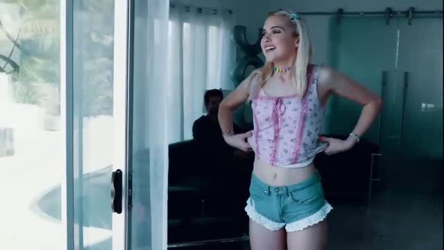 Chloe Cherry in pink corset top and denim shorts, smiling seductively
