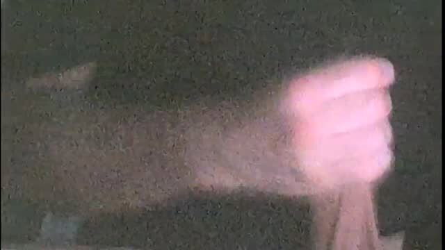 Blurry closeup of woman's clenched pink hand in dim light solo tease