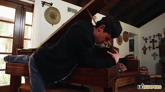 Nicolette Shea kneels by piano in hoodie, teasing hard cock bulge