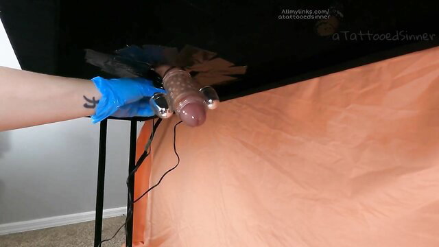 Tattooed hand in blue glove stretches balls on milking table machine