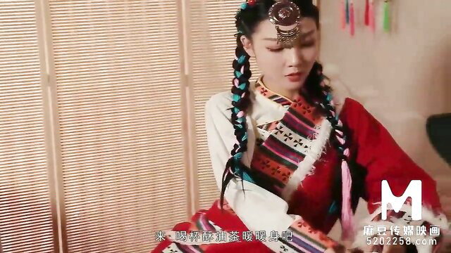 Asian beauty in traditional colorful dress with braids, seductive pose