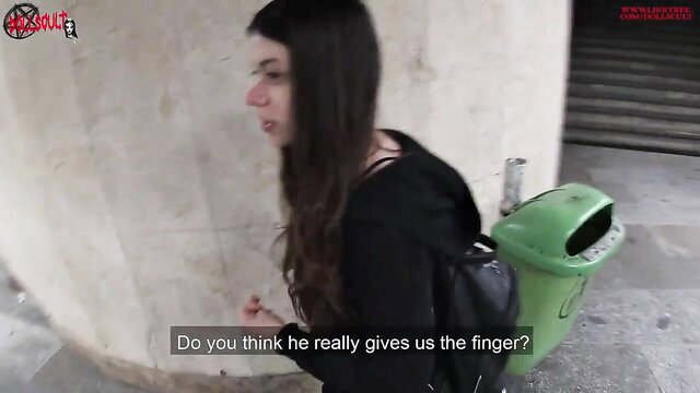 Brunette teen in tight black top and backpack by trash bin, smirking