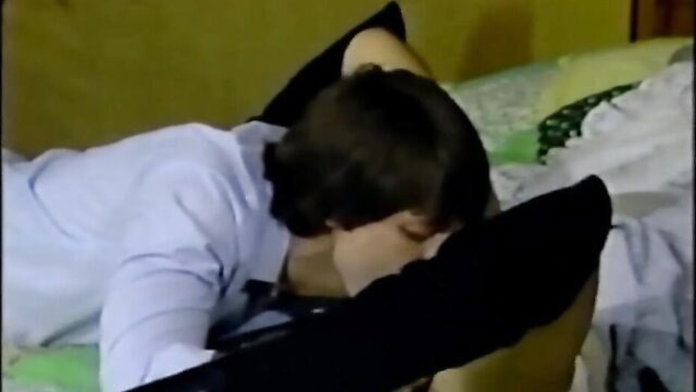 Woman lying face down on bed in white shirt and black pillow, upskirt tease