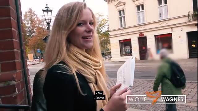Blonde Claudia with scarf holds paper on street in Wolf Wagner video