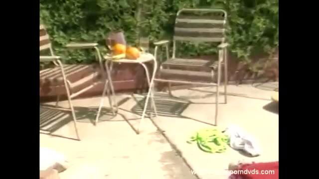 Trinity Loren by poolside with oranges, green bikini bottom on patio