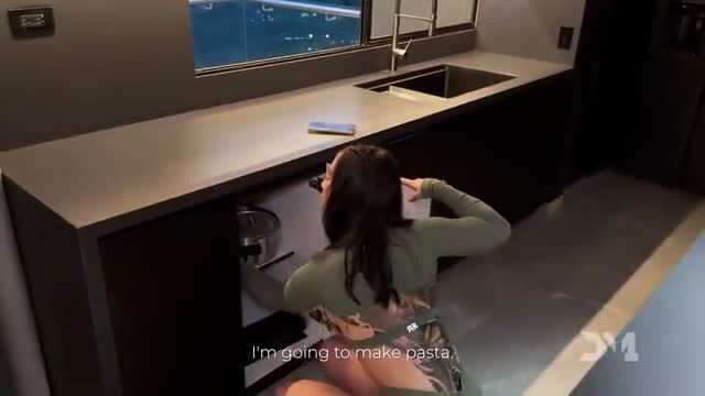 Iris Rodriguez bends over kitchen counter in tight top, making pasta