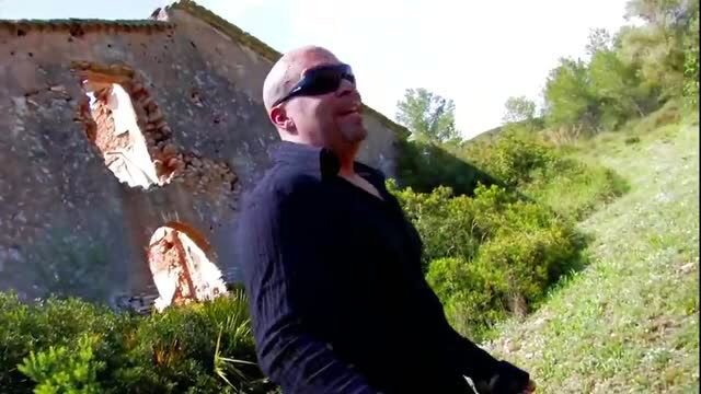 Bald man in sunglasses outdoors near ruined stone wall