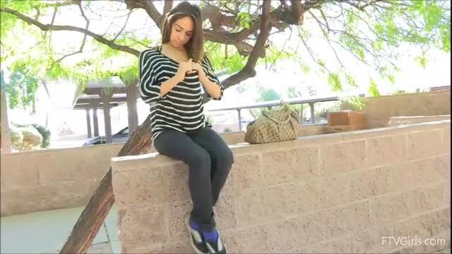 Sara sitting on wall, wearing striped top and leggings, phone in hand