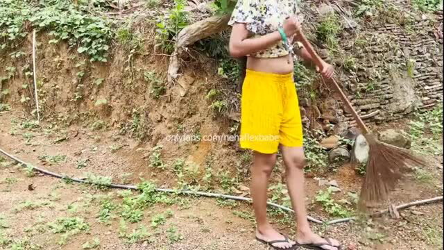Indian wife in yellow shorts holding broom outdoors