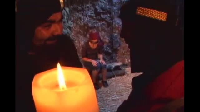Wax play scene with bound man in candlelit cave setting