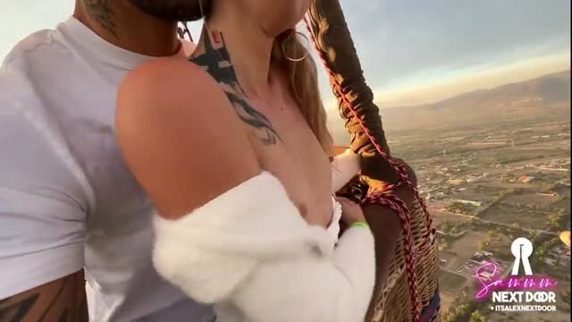 Tattooed couple embracing in hot air balloon over mountains